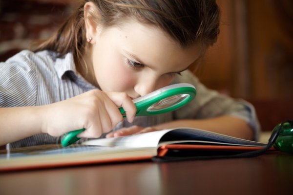 Niña leyendo con una lupa