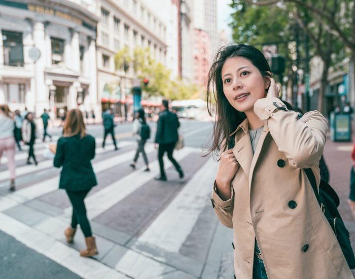 pretty woman looking around the city joyfully by the background of people crossing the road