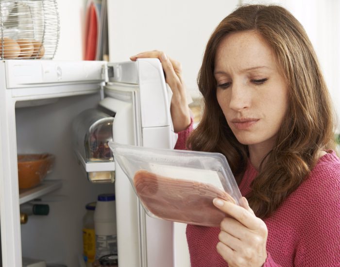 Concerned Woman Looking At Pre Packaged Meat