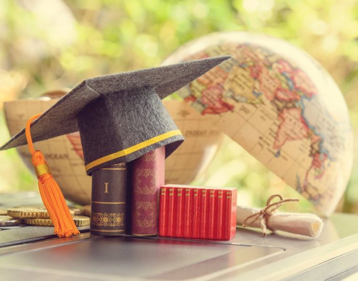 Key success in graduate study abroad program and open or expand world view experience concept : Graduation cap or hat, certificate or diploma, mini text books on a laptop computer, a half world globe.