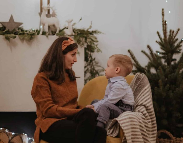 Merry Christmas and Happy Holidays! Pretty young woman spend good time together with her little boy in front of the fireplace.