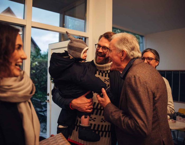 Unos abuelos en el recibidor de una casa, recibiendo a sus hijos y nietos